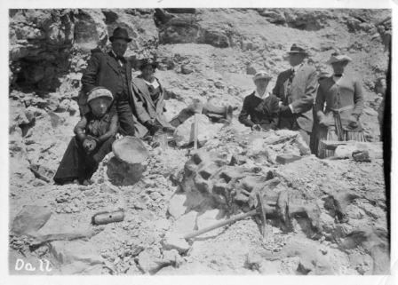 Black and white image of DeWeese with a group of people posing dinosaur vertebrae. Circa 1915.