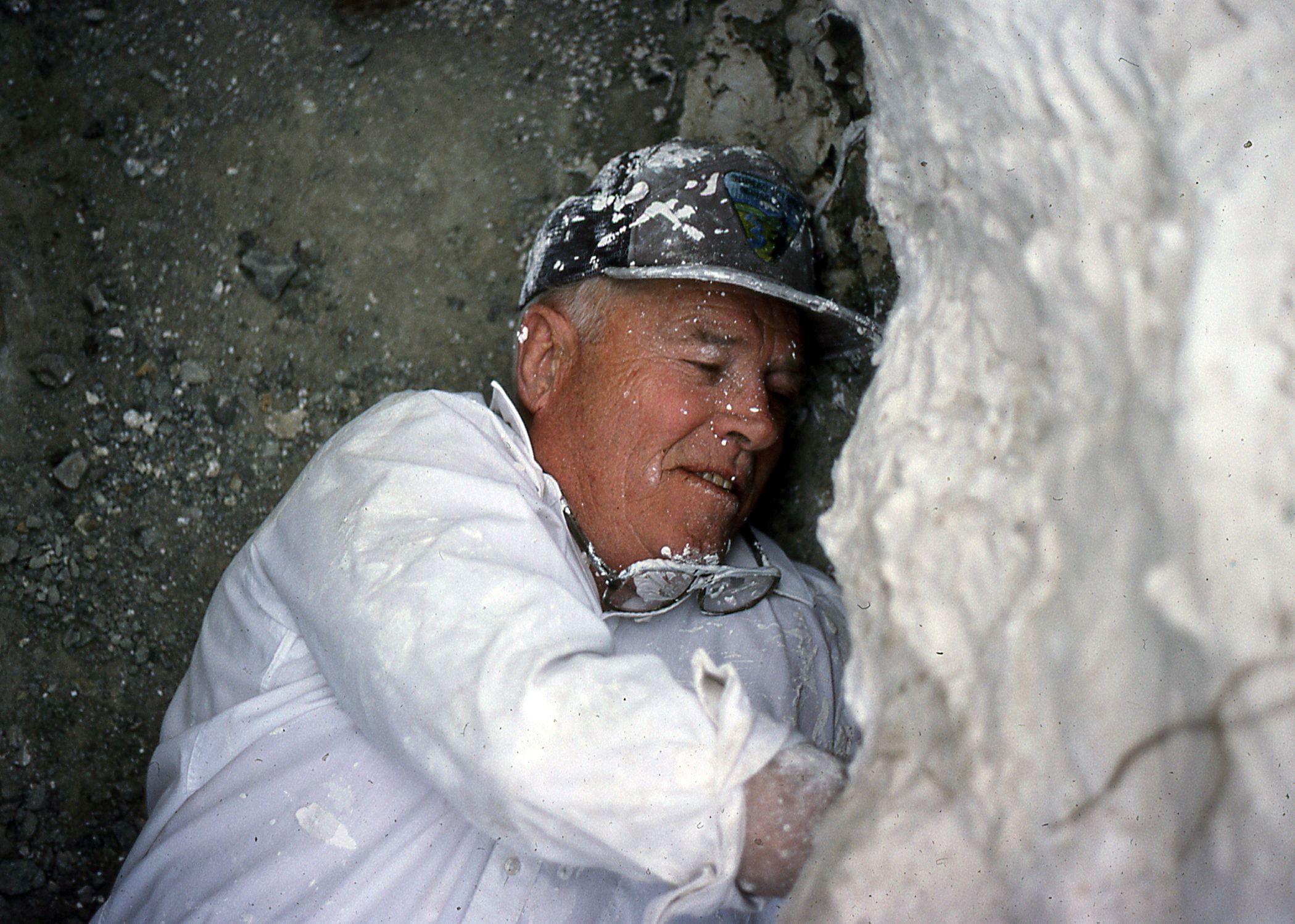 Color photo of a volunteer roofing the specimen of a stegosaurus fossil. Circa 1992.